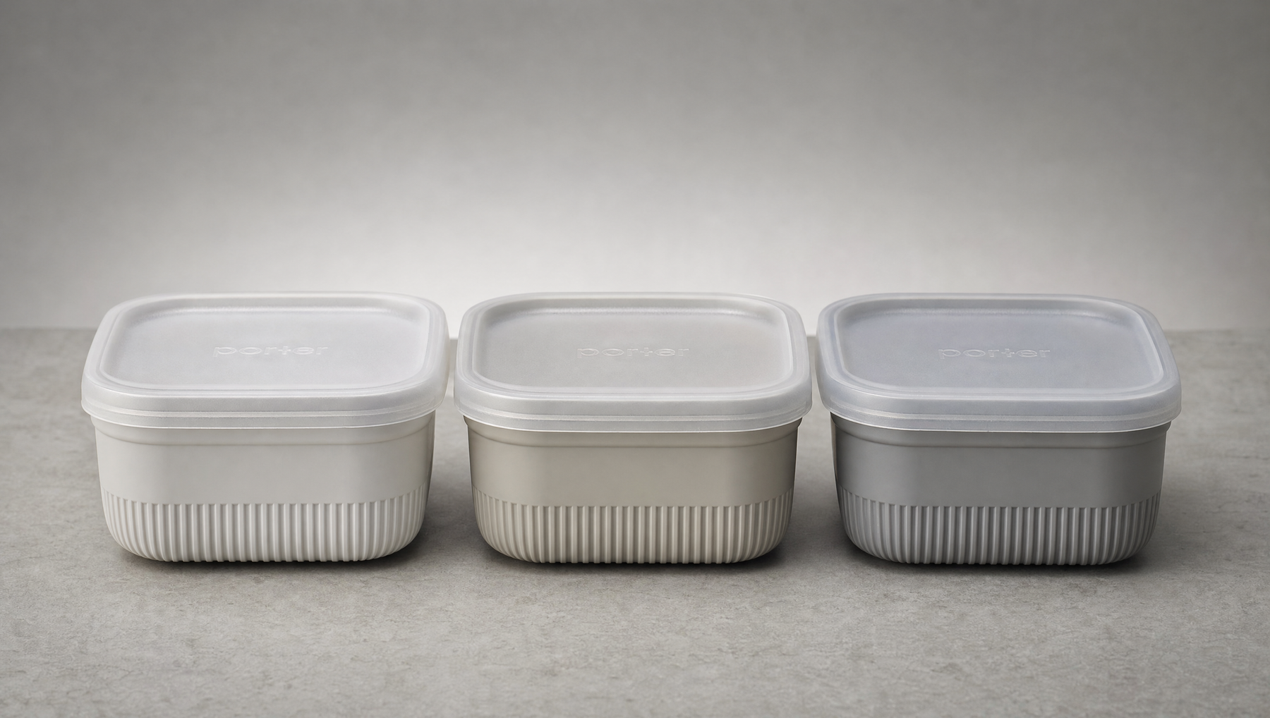 Three small food containers side by side on a neutral grey surface, soft daylight, compostable packaging comparison