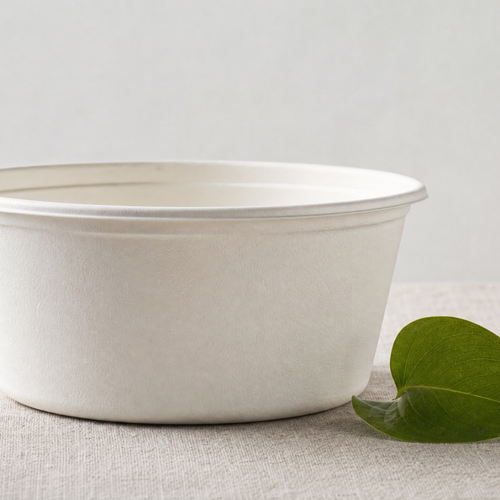 White compostable food container with a small green leaf next to it on neutral surface, sustainability claim compliance