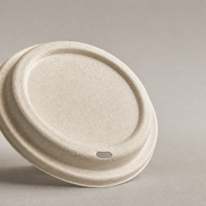 Compostable bagasse fibre coffee cup lid on neutral surface, product photography of PE PS and CPLA alternatives