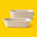 Stack of natural bagasse oval shallow salad bowls 650ml on yellow