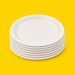 Stack of white bagasse 9 inch round plates, on yellow
