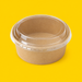 Clear PET lid fitted on a round kraft salad bowl, on yellow