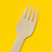 Close-up of a birchwood wooden fork, on yellow