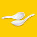 Two white bagasse Chinese soup spoons 140mm, on yellow