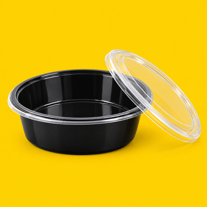 Black 7 inch round food container with its clear lid, on yellow