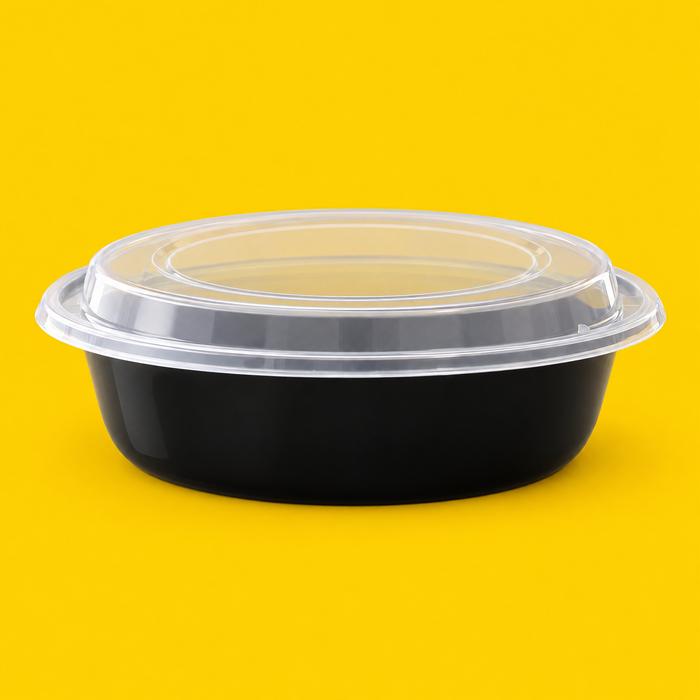 Black 9 inch round food container with clear lid, on yellow