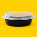 Black 9 inch round food container with clear lid, on yellow