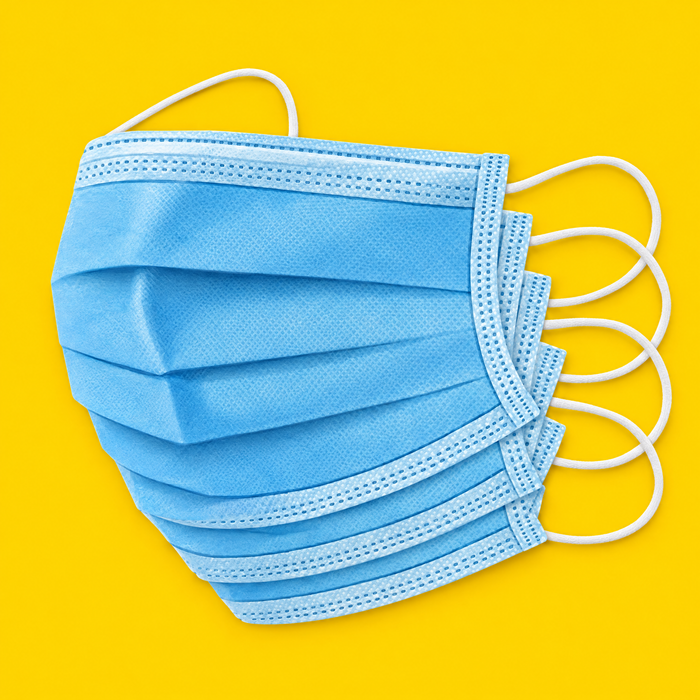 Stack of blue 3-ply disposable face masks, on yellow